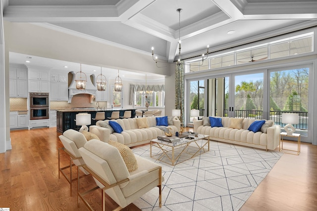 living room featuring coffered ceiling, crown molding, light hardwood / wood-style floors, and plenty of natural light