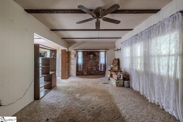 unfurnished living room featuring beamed ceiling, light colored carpet, and ceiling fan