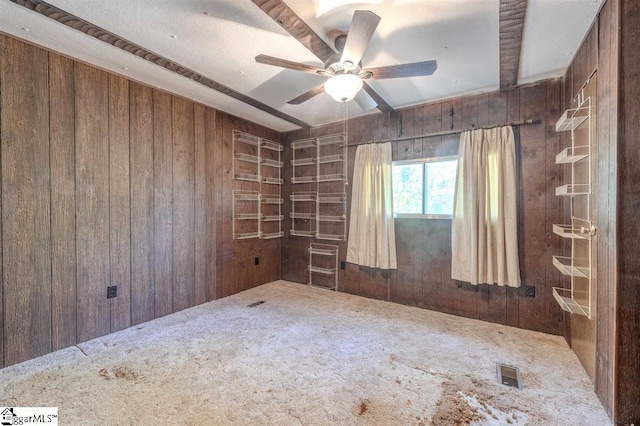 carpeted spare room with ceiling fan and wooden walls