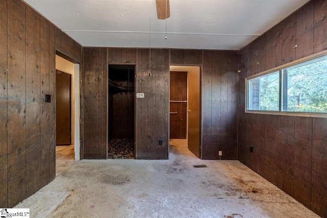 unfurnished room featuring wooden walls and ceiling fan