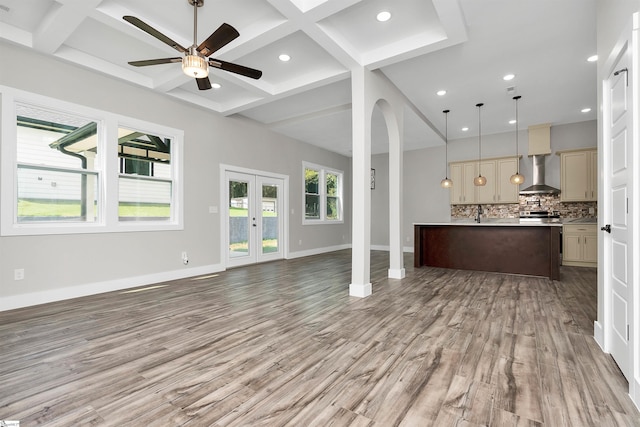 kitchen with wall chimney exhaust hood, pendant lighting, hardwood / wood-style flooring, and coffered ceiling