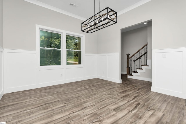 spare room with ornamental molding, a notable chandelier, and hardwood / wood-style flooring