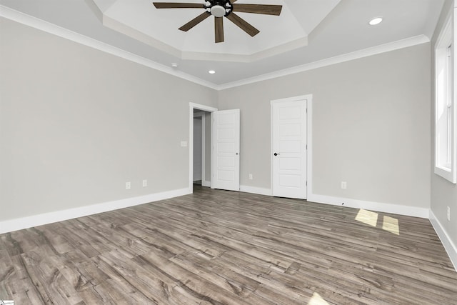 spare room with ornamental molding, hardwood / wood-style flooring, ceiling fan, and a tray ceiling