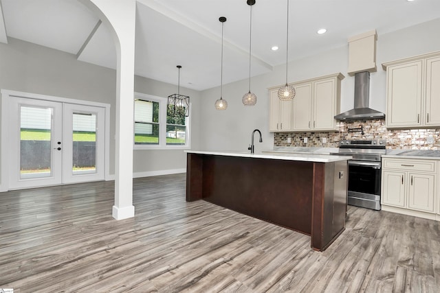 kitchen featuring light hardwood / wood-style floors, cream cabinets, wall chimney exhaust hood, and electric stove