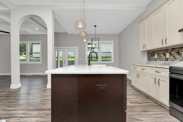 kitchen featuring hanging light fixtures, hardwood / wood-style floors, backsplash, beam ceiling, and light stone counters