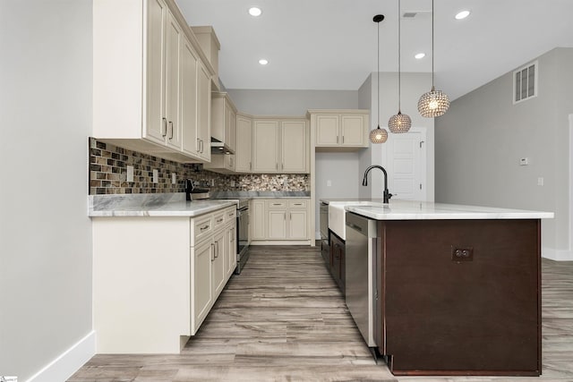 kitchen featuring tasteful backsplash, pendant lighting, stainless steel appliances, and light hardwood / wood-style flooring