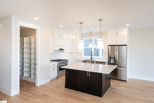 kitchen featuring a center island, white cabinets, hanging light fixtures, stainless steel appliances, and light hardwood / wood-style flooring