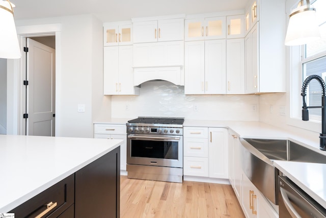 kitchen featuring decorative light fixtures, appliances with stainless steel finishes, light hardwood / wood-style flooring, tasteful backsplash, and white cabinetry