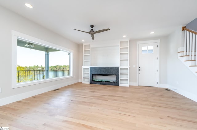 unfurnished living room with ceiling fan, light hardwood / wood-style floors, and built in features