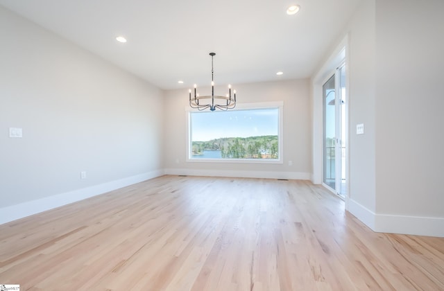 spare room featuring light hardwood / wood-style flooring and an inviting chandelier