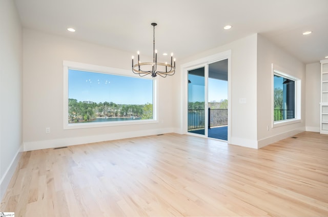 unfurnished room featuring a notable chandelier, light hardwood / wood-style flooring, and plenty of natural light