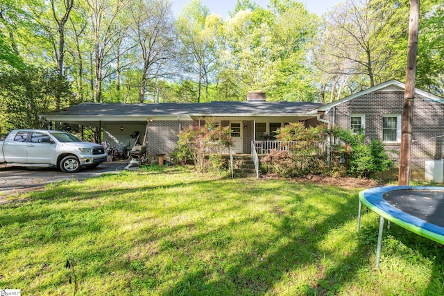 view of front of property with a front lawn, a trampoline, and a carport