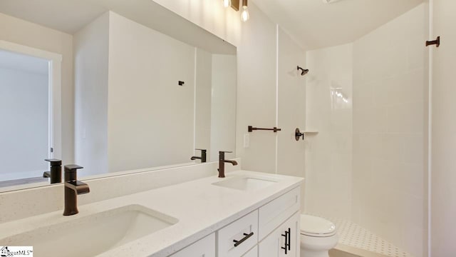 bathroom featuring double sink vanity, toilet, and tiled shower