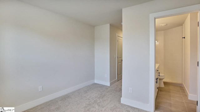 unfurnished bedroom with light colored carpet and connected bathroom