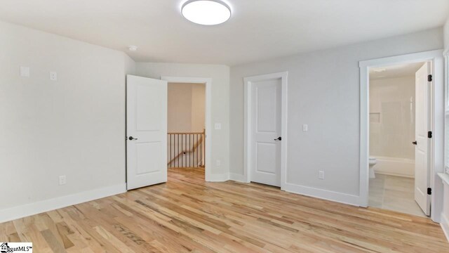 unfurnished bedroom with a closet, ensuite bathroom, and light tile flooring