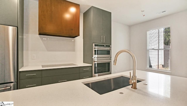 kitchen with stainless steel appliances, sink, and light stone counters