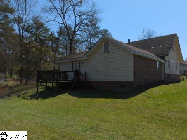 view of side of home with a wooden deck and a lawn