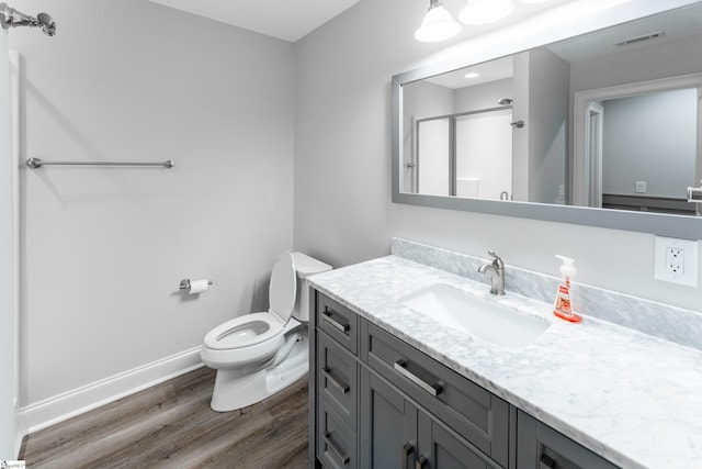 bathroom with wood-type flooring, vanity with extensive cabinet space, and toilet