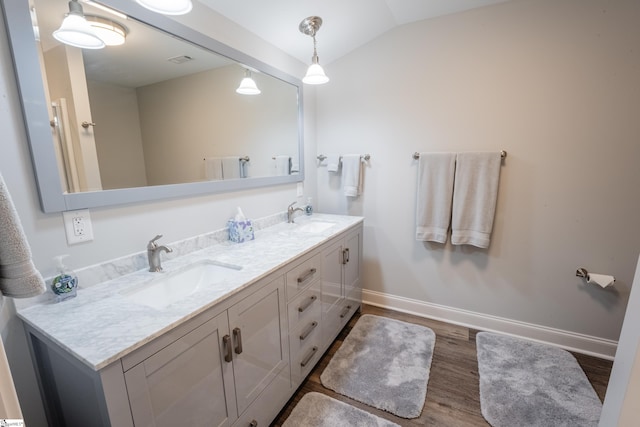 bathroom featuring hardwood / wood-style floors, lofted ceiling, oversized vanity, and double sink