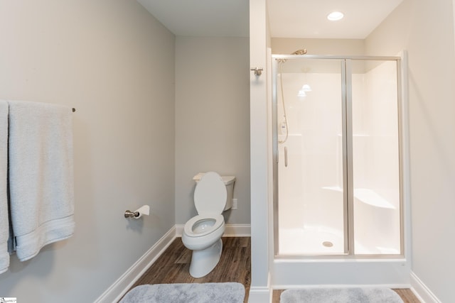 bathroom featuring hardwood / wood-style flooring, a shower with shower door, and toilet