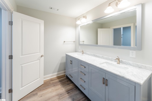 bathroom with wood-type flooring, oversized vanity, and dual sinks