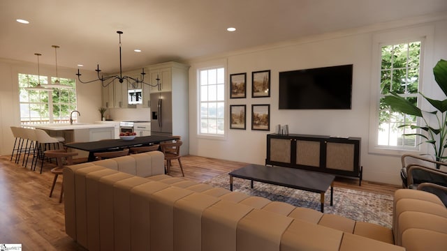 living room with plenty of natural light, sink, light hardwood / wood-style floors, and an inviting chandelier