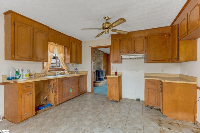 kitchen with ceiling fan, light tile flooring, brick wall, a textured ceiling, and sink