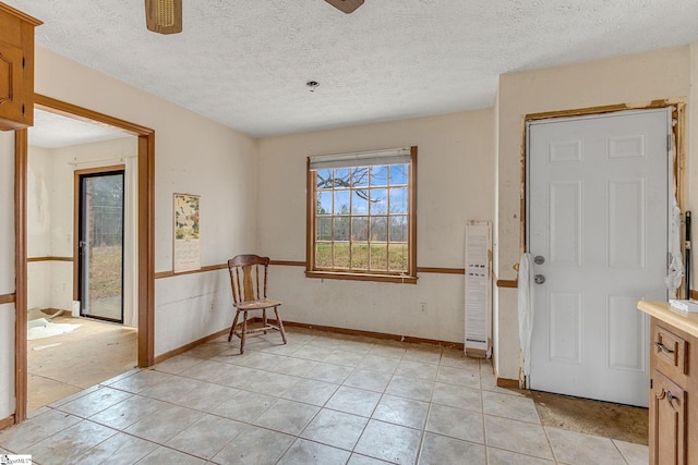 interior space featuring ceiling fan, light tile floors, and a textured ceiling