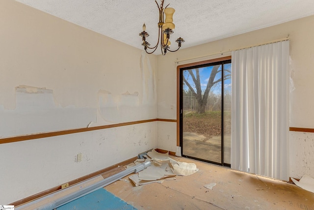 unfurnished room featuring a chandelier and a textured ceiling