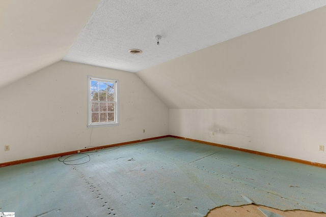 additional living space featuring lofted ceiling and a textured ceiling