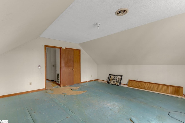 bonus room featuring lofted ceiling and a textured ceiling