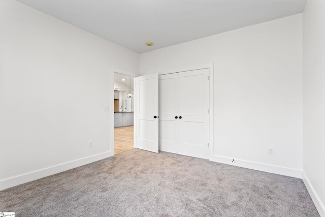 unfurnished bedroom featuring light colored carpet and a closet