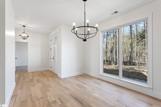 unfurnished dining area featuring light hardwood / wood-style flooring and a notable chandelier