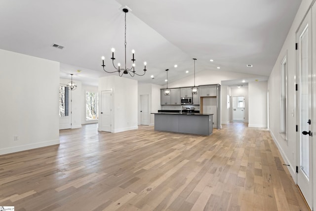 kitchen featuring gray cabinetry, an inviting chandelier, a center island with sink, pendant lighting, and light hardwood / wood-style floors