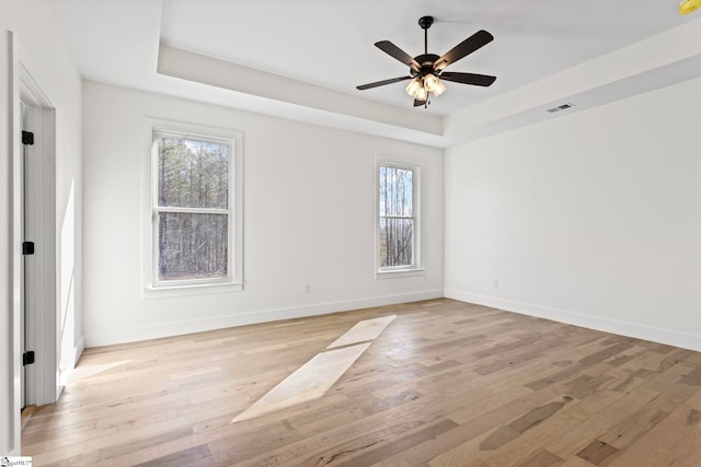 spare room featuring a tray ceiling, light hardwood / wood-style flooring, and ceiling fan