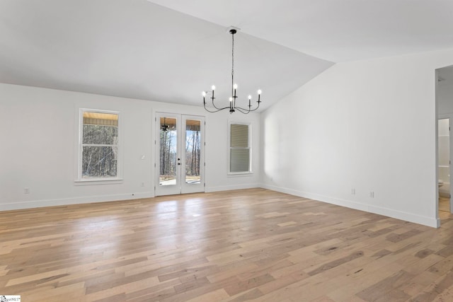 unfurnished dining area with vaulted ceiling, light hardwood / wood-style floors, french doors, and a chandelier