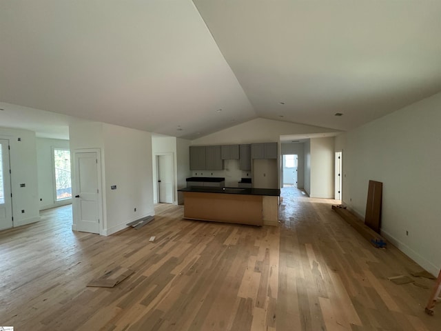 kitchen featuring gray cabinetry, a kitchen island, vaulted ceiling, and light wood-type flooring