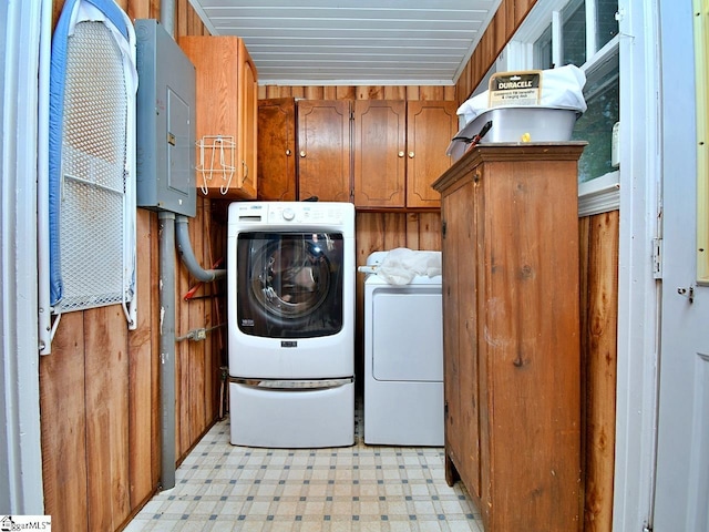 clothes washing area featuring cabinets, wooden walls, separate washer and dryer, and light tile floors