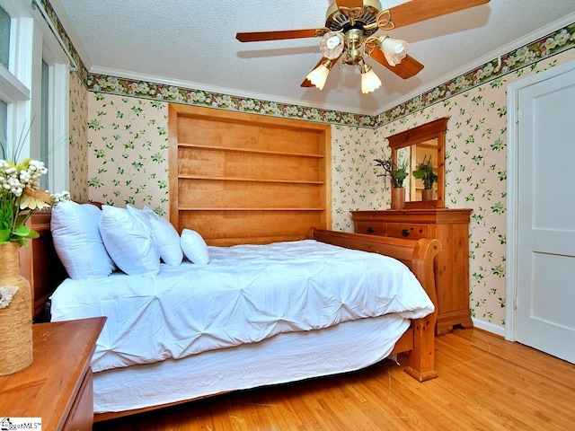 bedroom featuring ornamental molding, ceiling fan, light wood-type flooring, and a textured ceiling