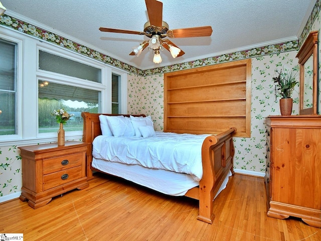 bedroom featuring ornamental molding, ceiling fan, light hardwood / wood-style flooring, and a textured ceiling