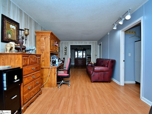 home office with a textured ceiling, light hardwood / wood-style flooring, and track lighting