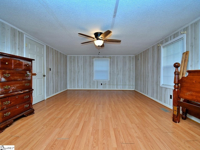 spare room with a textured ceiling, ceiling fan, and light wood-type flooring