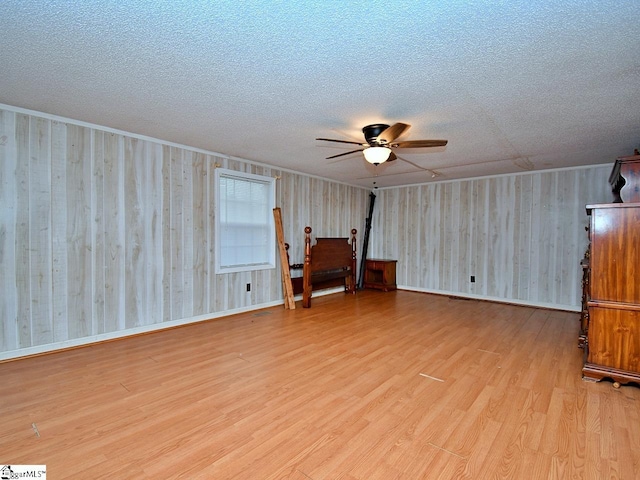 empty room with a textured ceiling, ceiling fan, and light hardwood / wood-style floors