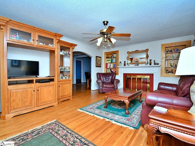 living room featuring light hardwood / wood-style flooring, ceiling fan, a textured ceiling, and a fireplace