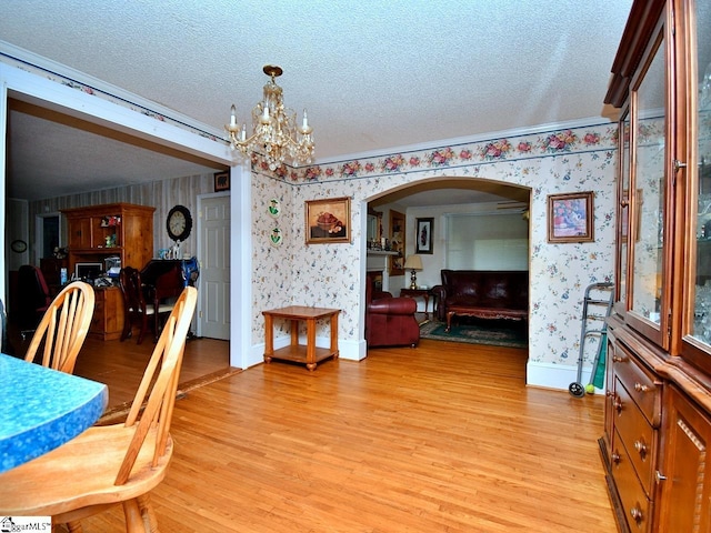 dining space with a textured ceiling, a notable chandelier, and light hardwood / wood-style floors