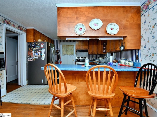 kitchen with fridge, light hardwood / wood-style floors, a breakfast bar, and stainless steel electric stove