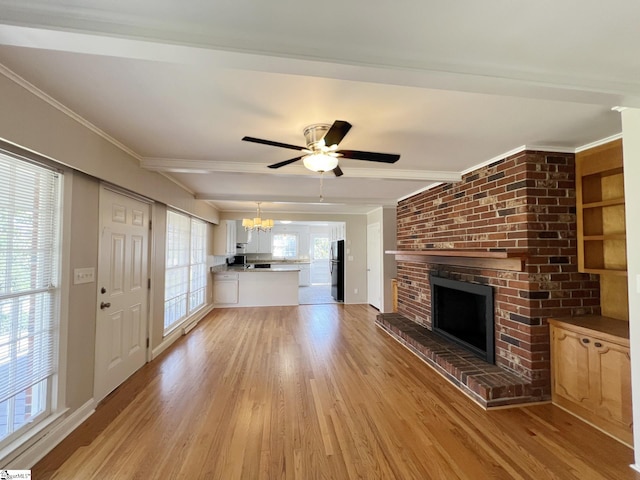 unfurnished living room featuring a brick fireplace, ceiling fan with notable chandelier, brick wall, ornamental molding, and wood-type flooring