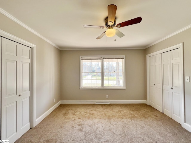 unfurnished bedroom with two closets, carpet floors, ceiling fan, and crown molding