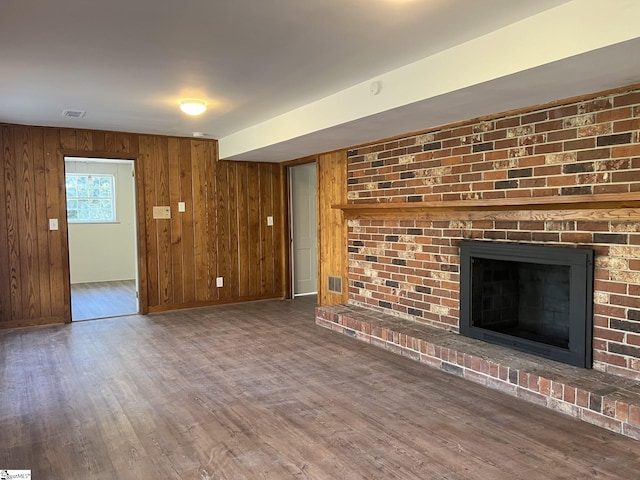 unfurnished living room featuring wood walls, dark hardwood / wood-style flooring, and a fireplace