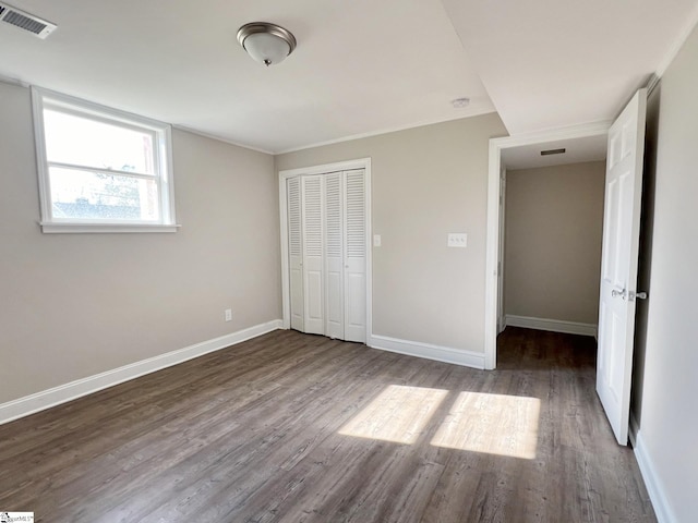 unfurnished bedroom with dark wood-type flooring and a closet